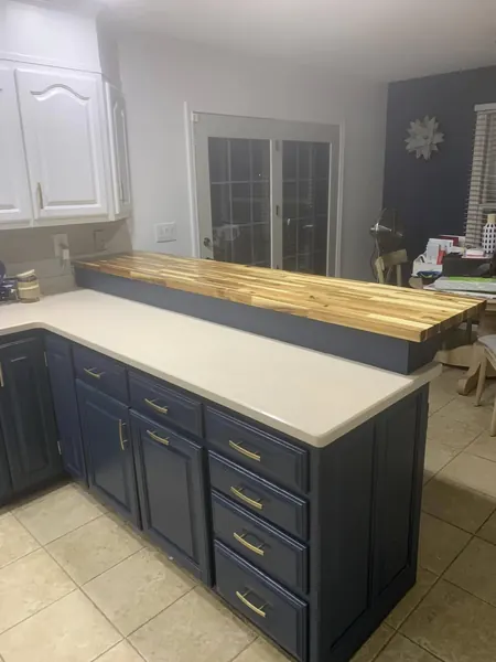 Navy kitchen island with a butcher-block counter and white cabinets
