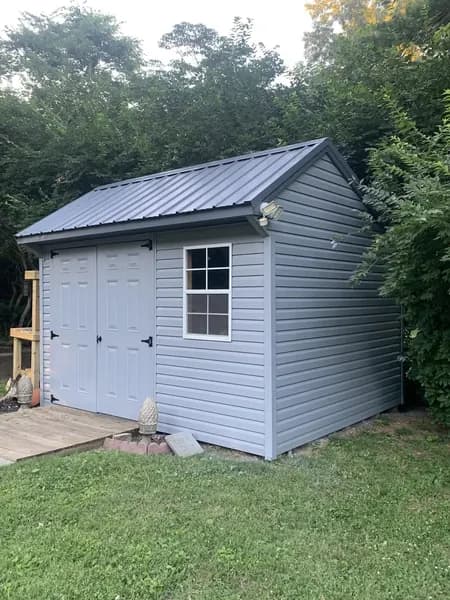 New gray storage shed with a metal roof and double doors